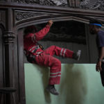 
              A member of the Cuban Red Cross jumps a wall as he leaves the Calvary Baptist Church, in Old Havana, Cuba, Wednesday, May 11, 2022. The May 6th explosion that devastated the Hotel Saratoga and killed dozens also badly damaged Cuba's most important Baptist church, which sits next door. (AP Photo/Ramon Espinosa)
            