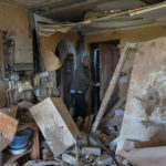 
              Resident Alexander, 67, checks the flat of his neighbour destroyed by shelling in Kutuzivka, near Kharkiv, eastern Ukraine, Friday, May 27, 2022. (AP Photo/Bernat Armangue)
            
