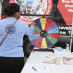 
              In this photo provided by The Navajo & Hopi Families COVID-19 Relief Fund, a campaign participant spins the prize wheel after showing she was fully vaccinated at the Window Rock Flea Market in Window Rock, Ariz., on Aug. 21, 2021. Arizona is the only state where rural vaccine rates outpaced more populated counties according to a recent report from the U.S. Centers for Disease Control and Prevention. Public health experts believe the unexpected trend was mainly fueled by a group that lost a disproportionate number of lives to COVID-19: Native Americans. (Mihio Manus/The Navajo & Hopi Families COVID-19 Relief Fund via AP)
            