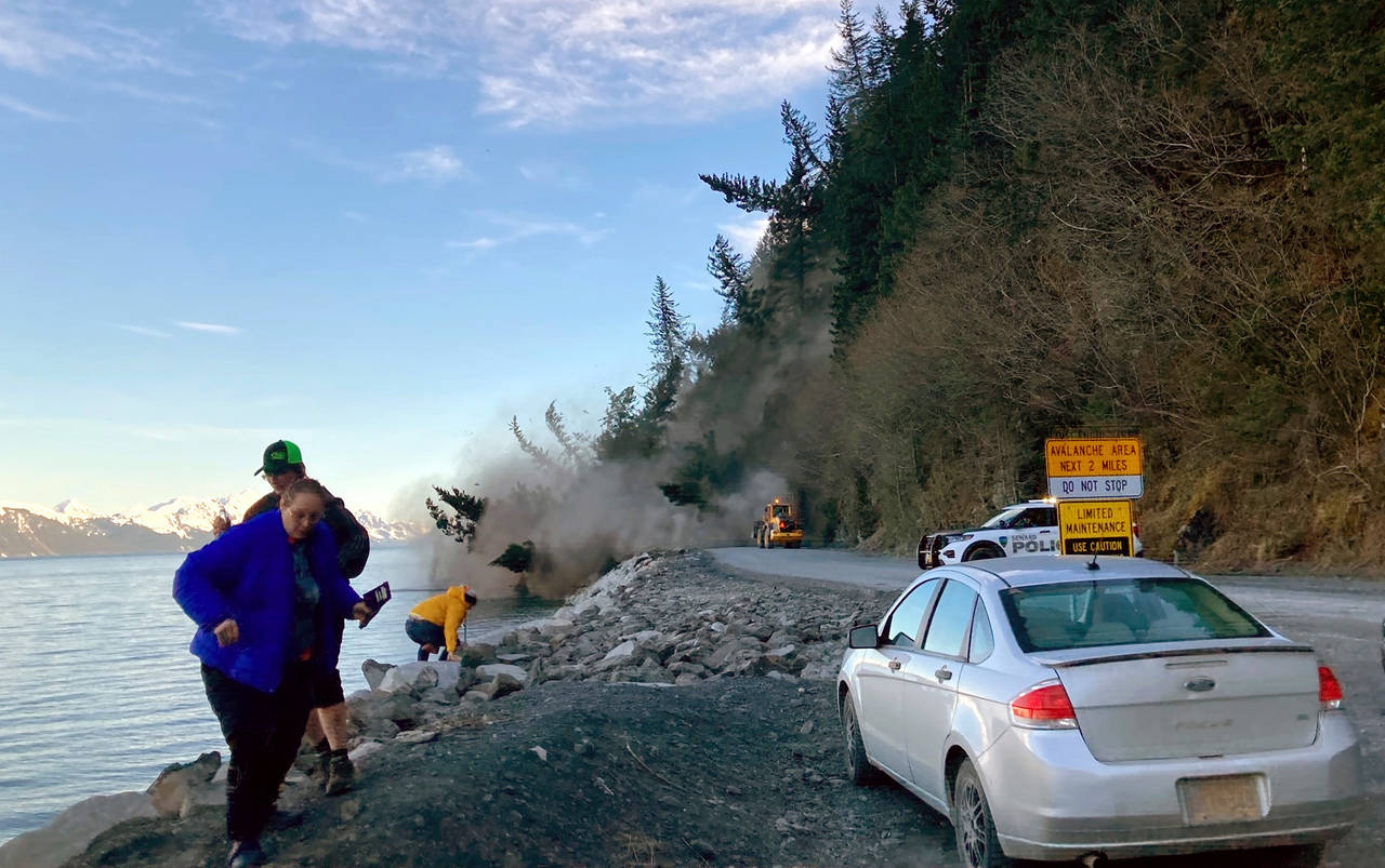 People run from a landslide just outside the downtown area of Seward, Alaska, May 7, 2022. There we...