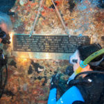 
              In this Sunday, May 15, 2022, photo provided by the Florida Keys News Bureau, Karen Berrios, right, watches Jon Hazelbaker install a commemorative plaque on the Spiegel Grove, a decommissioned 510-foot-long Naval Landing Ship Dock that was sunk in 2002 to become an artificial reef in the Florida Keys National Marine Sanctuary off Key Largo, Fla. Installation of the plaque was one of several activities that are being staged to mark the 20th anniversary of the sinking. Barrios' father and uncle served on the Spiegel Grove. (Frazier Nivens/Florida Keys News Bureau via AP)
            