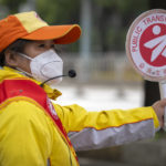 
              A crossing guard wearing a face mask stands at an intersection in Beijing, Wednesday, May 11, 2022. Shanghai reaffirmed China's strict "zero-COVID" approach to pandemic control Wednesday, a day after the head of the World Health Organization said that was not sustainable and urged China to change strategies. (AP Photo/Mark Schiefelbein)
            