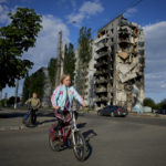 
              A girl rides a bicycle in front of houses ruined by shelling in Borodyanka, Ukraine, Tuesday, May 24, 2022. (AP Photo/Natacha Pisarenko)
            
