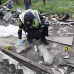 
              A police officer collects parts of shells during the exhumation of bodies of civilians killed by Russian shelling in the village of Malaya Rohan, on the outskirts of Kharkiv, Monday, May 16, 2022. (AP Photo/Andrii Marienko)
            