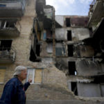 
              A woman walks in front of a building damaged by shelling in Horenka, on the outskirts of Kyiv, Ukraine, Wednesday, May 25, 2022. (AP Photo/Natacha Pisarenko)
            