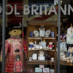
              FILE - Souvenir items for Britain's Queen Elizabeth II's Platinum Jubilee are displayed for sale in the front window of the Cool Britannia store near Buckingham Palace, in London, Thursday, May 26, 2022. Britain is getting ready for a party featuring mounted troops, solemn prayers — and a pack of dancing mechanical corgis. The nation will celebrate Queen Elizabeth II’s 70 years on the throne this week with four days of pomp and pageantry in central London. (AP Photo/Matt Dunham, File)
            