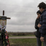 
              Yura Nechyporenko, 15, hugs his uncle Andriy Nechyporenko above the grave of his father Ruslan Nechyporenko at the cemetery in Bucha, on the outskirts of Kyiv, Ukraine, on Thursday, April 21, 2022. The teen survived an execution attempt by Russian soldiers while his father was killed, and now his family seeks justice. (AP Photo/Petros Giannakouris)
            