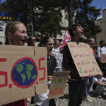 
              Climate activists perform with posters during a climate protest alongside the World Economic Forum in Davos, Switzerland, Thursday, May 26, 2022. The annual meeting of the World Economic Forum is taking place in Davos from May 22 until May 26, 2022. (AP Photo/Evgeniy Maloletka)
            