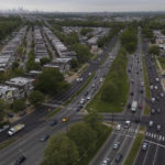
              The Philadelphia skyline, top, is seen at a distance as vehicular traffic flows along Roosevelt Boulevard at the intersection with Whitaker Avenue, Thursday, May 12, 2022, in Philadelphia. Roosevelt Boulevard is an almost 14-mile maze of chaotic traffic patterns that passes through some of the city's most diverse neighborhoods and Census tracts with the highest poverty rates. Driving can be dangerous with cars traversing between inner and outer lanes, but biking or walking on the boulevard can be even worse with some pedestrian crossings longer than a football field and taking four light cycles to cross. (AP Photo/Julio Cortez)
            
