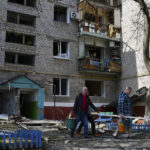 
              Men walk past an apartment building destroyed by night shelling in Kramatorsk, Ukraine, Thursday, May 5, 2022. (AP Photo/Andriy Andriyenko)
            