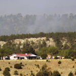 
              Smoke rises on a ridge behind homes on the outskirts of Las Vegas, N.M., on May 3, 2022. Flames raced across more of New Mexico's pine-covered mountainsides Tuesday, charring more than 217 square miles over the last several weeks. (AP Photo/Thomas Peipert)
            