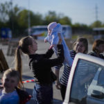 
              A woman holds up a baby as a family who fled from Enerhodar is reunited upon their arrival to a reception center for displaced people in Zaporizhzhia, Ukraine, Friday, May 6, 2022. Thousands of Ukrainian continue to leave Russian occupied areas. (AP Photo/Francisco Seco)
            