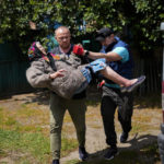 
              A woman is carried from her home in an evacuation by volunteers of Vostok SOS charitable organisation in Bakhmut, eastern Ukraine, Friday, May 27, 2022. Volunteers have been racing to evacuate as many civilians as possible, particularly the elderly and those with mobility issues, as Russian forces make advances in the region. (AP Photo/Francisco Seco)
            