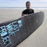 
              Dan Fischer, of Newport, R.I., sits for a photograph with his surfboard on Easton's Beach, in Newport, Wednesday, May 18, 2022. Fischer, 42, created the One Last Wave Project in January 2022 to use the healing power of the ocean to help families coping with a loss, as it helped him following the death of his father. Fischer places names onto his surfboards, then takes the surfboards out into the ocean as a way to memorialize the lost loved ones in a place that was meaningful to them. (AP Photo/Steven Senne)
            