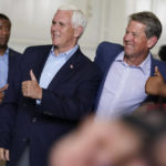 
              Former Vice President Mike Pence, second from left, and Georgia Gov. Brian Kemp, center, pose for a photo with a supporter after a Get Out the Vote Rally,  on the eve of gubernatorial and other primaries in the state, on Monday, May 23, 2022, in Kennesaw, Ga.  (AP Photo/Brynn Anderson)
            