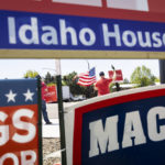 
              Robert Koellisch holds an American flag in front of political signs for Idaho's Primary Election in Eagle, Idaho, Tuesday, May 17, 2022. (AP Photo/Kyle Green)
            