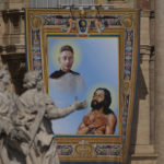 
              The tapestry depicting Titus Brandsma (1881-1942), top, and Lazzaro alias Devasahayam (1712-1752) hangs in St. Peter's Square at The Vatican, Sunday, May 15, 2022, during their canonization mass celebrated by Pope Francis. Francis created ten new saints on Sunday, rallying from knee pain that has forced him to use a wheelchair to preside over the first canonization ceremony at the Vatican in over two years. (AP Photo/Gregorio Borgia)
            