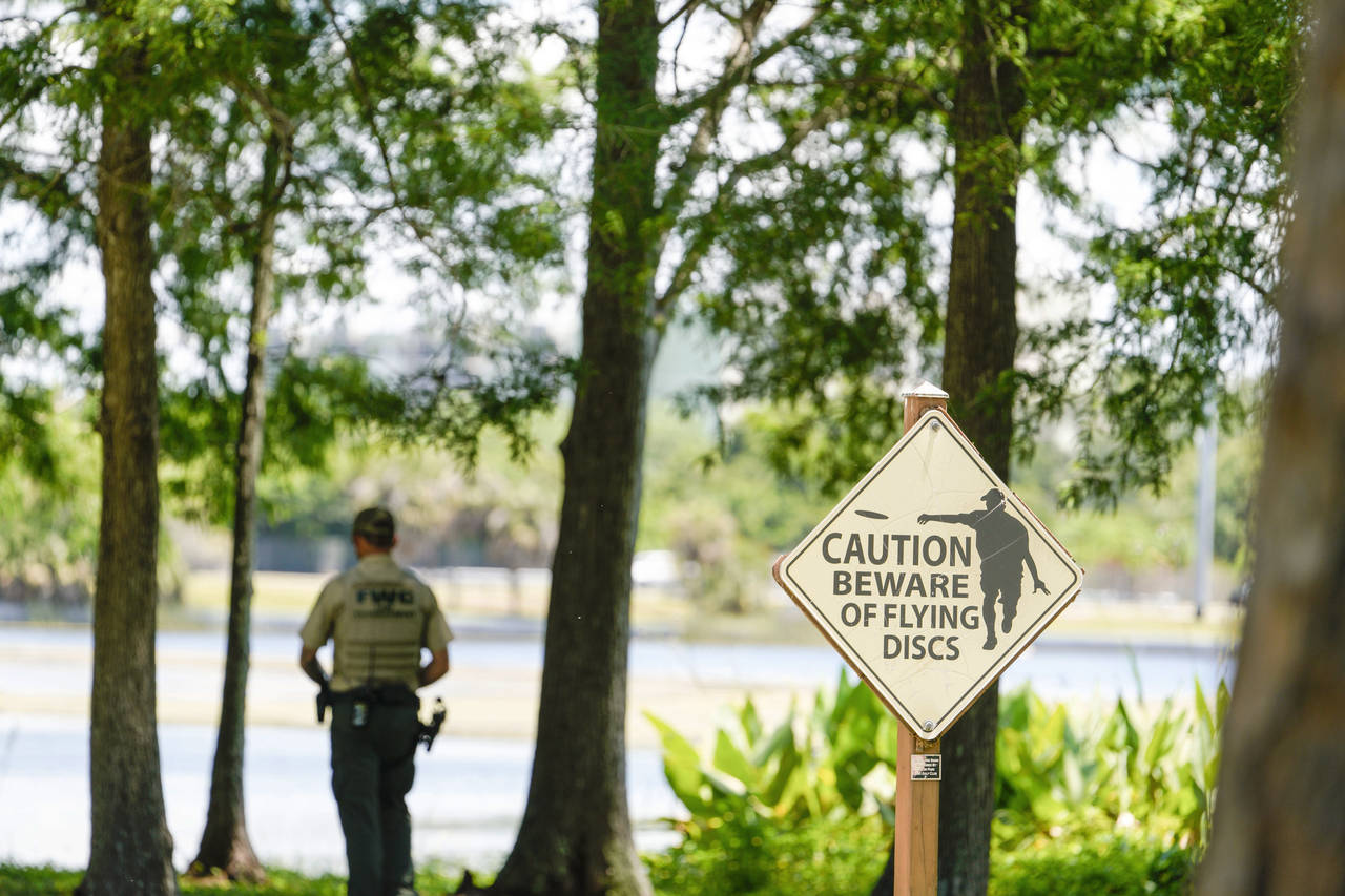 A Florida Fish and Wildlife Conservation Commission officers stands by a lake in John S. Taylor Par...