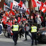 
              People march past police at a demonstration, part of a convoy-style protest participants are calling "Rolling Thunder," in Ottawa, Ontario, on Saturday, April 30, 2022. (Patrick Doyle/The Canadian Press via AP)
            