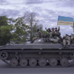 
              Ukrainian serviceman wave a flag with writing reading in Ukrainian "Glory to Ukraine", top, and "Death to the enemies"        as they ride atop of a tank in the Kharkiv region, eastern Ukraine, Monday, May 16, 2022. (AP Photo/Bernat Armangue)
            