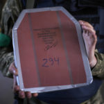 
              A Ukrainian soldier holds his body armor metal piece with a personal inscription that reads in Ukrainian: "To my good friend from Hennadii. Come back to get some hugs", at a facility producing material for Ukrainian soldiers in Zaporizhzhia, Ukraine, Friday, May 6, 2022. An old industrial complex in the southeastern Ukrainian riverside city of Zaporizhzhia has become a hive of activity for volunteers producing everything from body armor to camouflage nets, anti-tank obstacles to heating stoves and rifle slings for Ukrainian soldiers fighting the Russian invasion. (AP Photo/Francisco Seco)
            