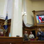 
              In this image released by the Ukrainian Presidential Press Office, Ukrainian President Volodymyr Zelenskyy, left, applauds as a screen shows Britain's Prime Minister Boris Johnson via videolink, during a session at Ukraine's parliament, in Kyiv, Ukraine, Tuesday, May 3, 2022. (Ukrainian Presidential Press Office via AP)
            
