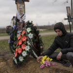 
              Yura Nechyporenko, 15, places a chocolate at the grave of his father Ruslan Nechyporenko at the cemetery in Bucha, on the outskirts of Kyiv, Ukraine, on Thursday, April 21, 2022. The teen survived an execution attempt by Russian soldiers while his father was killed, and now his family seeks justice. (AP Photo/Petros Giannakouris)
            