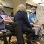 
              Community members opposed to a proposal to build a $1.4 billion desalination plant in Huntington Beach sit with signs at a California Coastal Commission hearing in Costa Mesa, Calif., Thursday May 12, 2022. For more than two decades, California's Orange County has debated whether to build a seaside plant to convert the Pacific Ocean's salt water into drinking water in hopes of buffering against droughts like the one now gripping the nation's most populous state. (AP Photo/Amy Taxin)
            