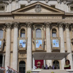 
              The tapestries depicting ten new saints, from left and top to bottom, Marie Rivier (1768-1838), Maria Francesca di Gesù Rubatto (1844-1904), César de Bus (1544-1607), Luigi Maria Palazzolo (1827-1886), Titus Brandsma (1881-1942), Lazzaro alias Devasahayam (1712-1752), Giustino Maria Russolillo (1891-1955), Charles de Foucauld (1858-1916), Maria di Gesù Santocanale (1852-1923), and Maria Domenica Mantovani (1862-1934) hang in St. Peter's Square at The Vatican, Sunday, May 15, 2022, during their canonization mass celebrated by Pope Francis. Francis created ten new saints on Sunday, rallying from knee pain that has forced him to use a wheelchair to preside over the first canonization ceremony at the Vatican in over two years. (AP Photo/Gregorio Borgia)
            