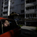 
              Children wait in a car for their relatives in front of a building destroyed by attacks, in Borodyanka, on the outskirts of Kyiv, Ukraine, Tuesday, May 31, 2022. (AP Photo/Natacha Pisarenko)
            