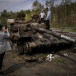 
              FILE - Maksym, 3, is photographed with his brother, Dmytro, 16, on top of a destroyed Russian tank, on the outskirts of Kyiv, Ukraine, May 8, 2022. Three months after it invaded Ukraine hoping to overtake the country in a blitz, Russia has bogged down in what increasingly looks like a war of attrition with no end in sight. (AP Photo/Emilio Morenatti, File)
            