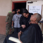 
              Wildfire evacuee Domingo Martinez gets a haircut from Jessica Aragón outside an emergency shelter in Las Vegas, N.M., on Saturday, May 7, 2022. Martinez left his home in a wooded rural area northwest of Las Vegas and stayed in a safer neighborhood with his son. The people lined up behind him are meeting with federal officials for help with assistance claims. (AP Photo/Cedar Attanasio)
            