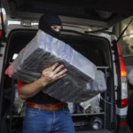 
              FILE - A masked policeman carries packs of cocaine, at the organized crime prosecutor' office in Bucharest, Romania, on July 1, 2016. Records amounts of cocaine are being seized in Europe while manufacturing of the banned stimulant drug is now taking place inside the the European Union, officials in charge of fighting and monitoring drugs use in the bloc warned on Friday, May 6, 2022. (AP Photo/Andreea Alexandru)
            