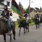 
              Mounted members of the Buffalo Soldiers of Seattle historical organization enter the Marketplace vendors' lane to open the Juneteenth Celebration Festival called Omo Africa, on Sunday, June 19, 2022, at Rebecca Howard Park in Olympia, Wash. (Steve Bloom/The Olympian via AP)
            