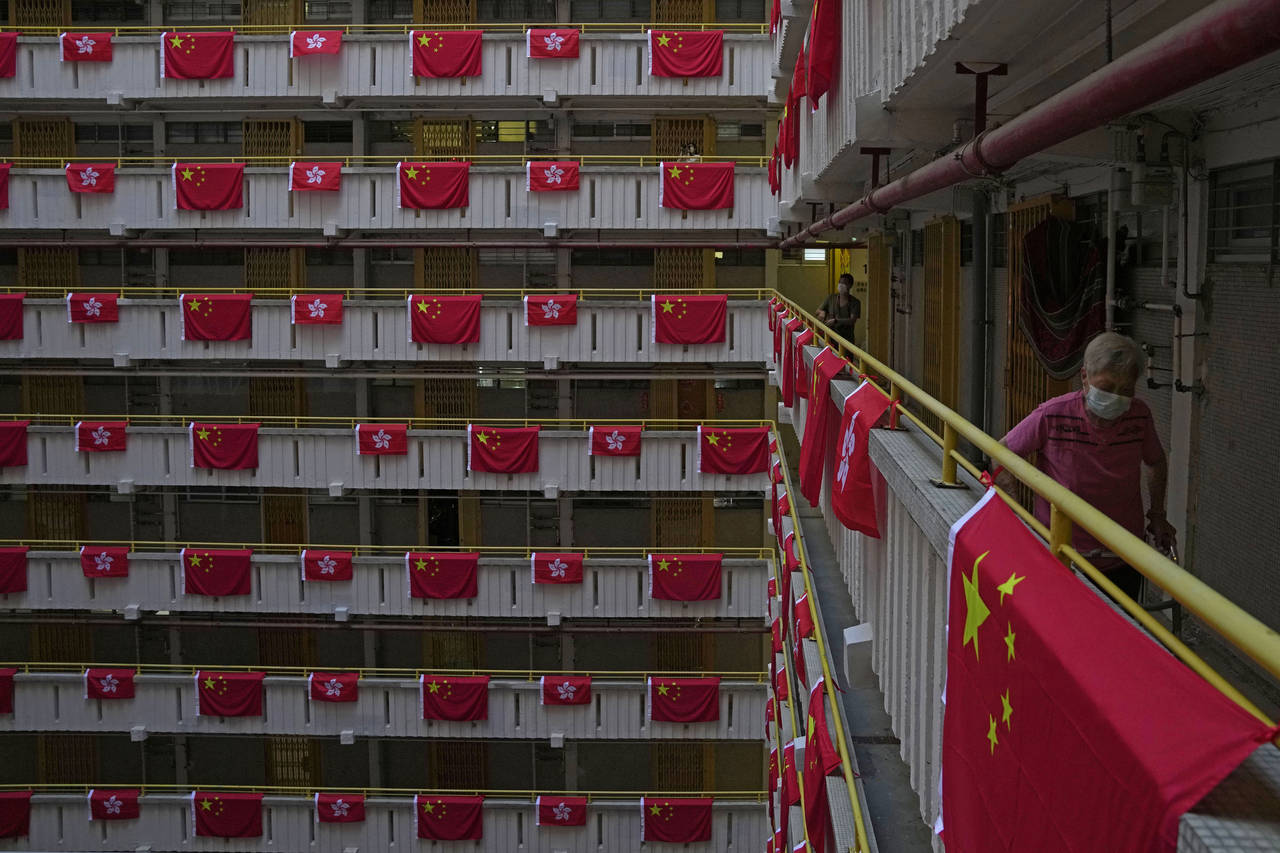 A resident walks besides the Chinese and Hong Kong flags hanging from a residential building to cel...
