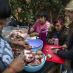 
              Members of the Frente Popular Dario Santillan social organization cut pieces of pork to prepare a bread with fried pork rinds to raise money in the patio of the Little Lions soup kitchen, in the Carmen de Alvear neighborhood, in the Tigre district, on the outskirts of Buenos Aires, Argentina, Monday, May 23, 2022. A portion of the bread is given to poverty stricken families in the community. (AP Photo/Rodrigo Abd)
            