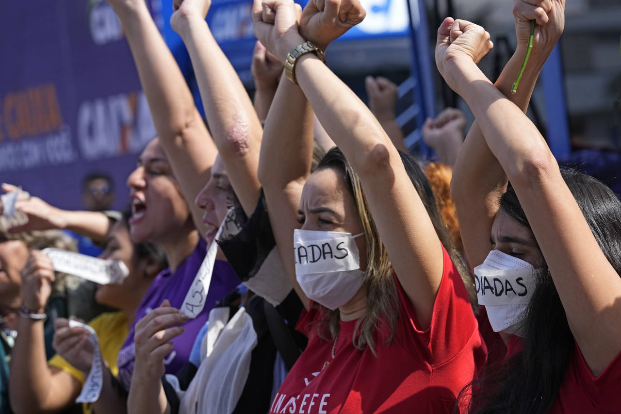 Employees of Caixa Economica Federal bank raise their arms and wear stickers over their mouths, tha...