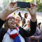 
              Royal fans take a selfie as they stand alongside the Mall leading to Buckingham Palace in London, Thursday June 2, 2022, on the first of four days of celebrations to mark the Platinum Jubilee. The events over a long holiday weekend in the U.K. are meant to celebrate the monarch's 70 years of service. (AP Photo/David Cliff)
            