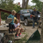 
              Harlee Holmes, 8, right, helps her bother, Creek, 3, put his shoes on as the family packs up to leave their home left damaged by severe flooding in Fromberg, Mont., Friday, June 17, 2022. (AP Photo/David Goldman)
            