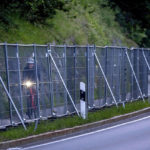 
              A man rides his bike behind a fence at the road to Garmisch-Partenkirchen, Germany Monday, June 27, 2022. The G-7 leaders will begin Monday's session of their three-day summit with a focus on Ukraine. (AP Photo/Michael Probst)
            