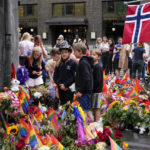 
              People lay flowers under rain at the scene of a shooting in central of Oslo, Norway, Sunday, June 26, 2022. Norwegian police say they are investigating an overnight shooting in Oslo that killed two people and injured more than a dozen as a case of possible terrorism. In a news conference Saturday, police officials said the man arrested after the shooting was a Norwegian citizen of Iranian origin who was previously known to police but not for major crimes. (AP Photo/Sergei Grits)
            
