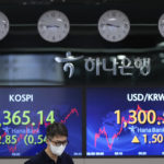 
              A currency trader walks by the screens showing the Korea Composite Stock Price Index (KOSPI), left, and the foreign exchange rate between U.S. dollar and South Korean won at a foreign exchange dealing room in Seoul, South Korea, Thursday, June 30, 2022. Asian stock markets were mixed Thursday after the U.S. economy contracted and China reported stronger factory activity. (AP Photo/Lee Jin-man)
            