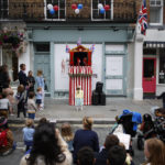 
              A young girl looks up at a Punch and Judy show during a public street party in Elizabeth Street in central London, Sunday June 5, 2022, on the last of four days of celebrations to mark the Platinum Jubilee. Street parties are set to be held across the country in what is being called The Big Jubilee Lunch. The events over a long holiday weekend in the U.K. have celebrated Queen Elizabeth II's 70 years of service. (AP Photo/David Cliff)
            