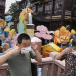 
              Visitors to the Yu Garden Mall put their masks on after posing for photos, Thursday, June 2, 2022, in Shanghai. Traffic, pedestrians and joggers reappeared on the streets of Shanghai on Wednesday as China's largest city began returning to normalcy amid the easing of a strict two-month COVID-19 lockdown that has drawn unusual protests over its heavy-handed implementation. (AP Photo/Ng Han Guan)
            