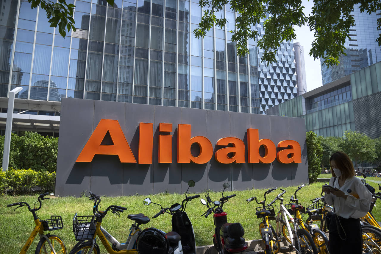 FILE - A woman walks past the offices of Chinese technology firm Alibaba in Beijing, on Aug. 10, 20...