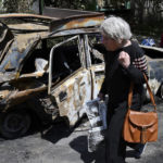 
              An elderly woman walks past a car damaged by an overnight missile strike in Sloviansk, Ukraine, Tuesday, May 31, 2022. (AP Photo/Andriy Andriyenko)
            