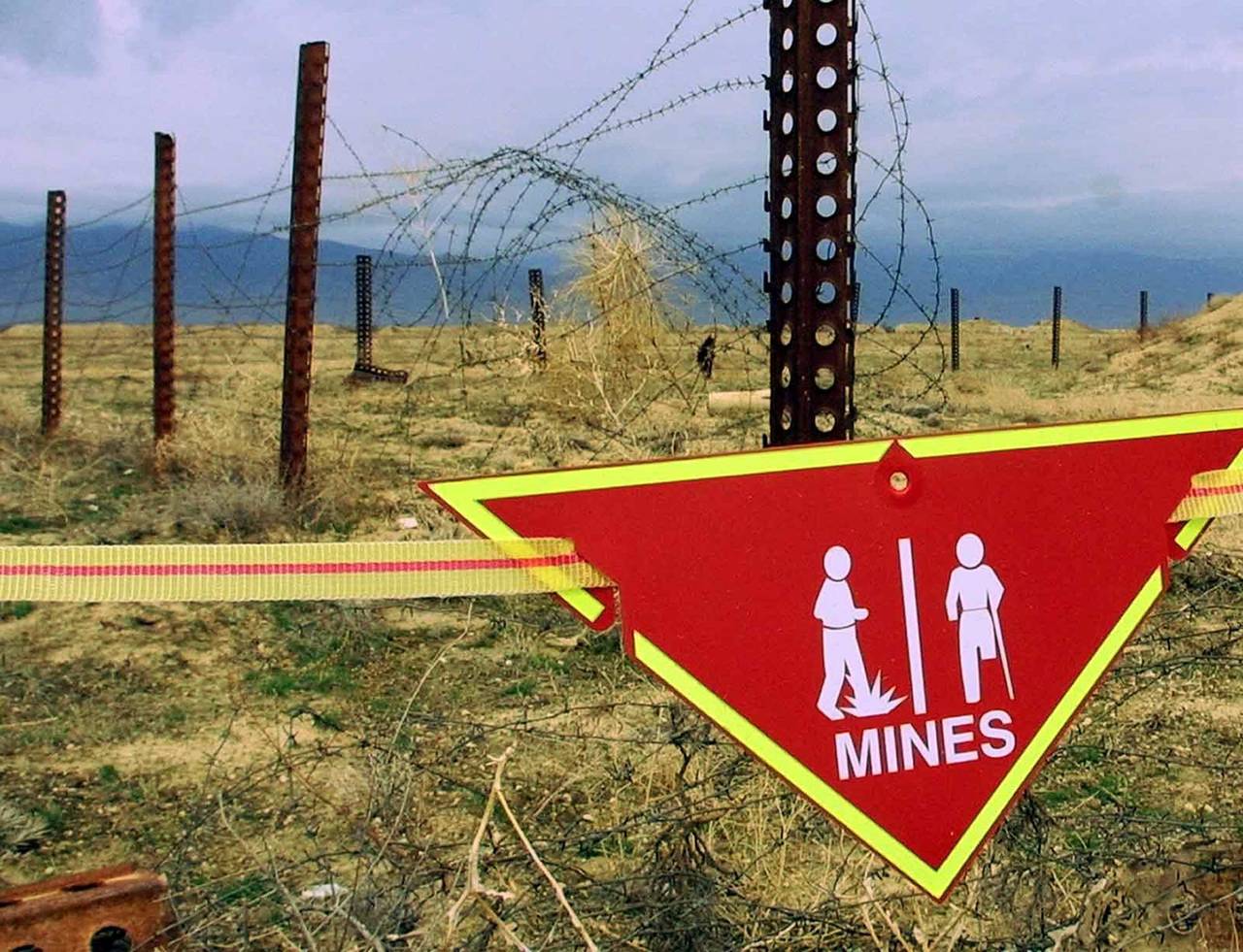 FILE - An international sign warning about mines hangs beside a minefield at Bagram Air Base on, Ma...