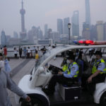 
              A police patrol vehicle monitors the crowd along the bund, Wednesday, June 1, 2022, in Shanghai. Traffic, pedestrians and joggers reappeared on the streets of Shanghai on Wednesday as China's largest city began returning to normalcy amid the easing of a strict two-month COVID-19 lockdown that has drawn unusual protests over its heavy-handed implementation. (AP Photo/Ng Han Guan)
            