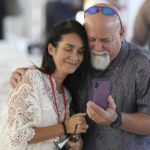 
              Two attendees gather around a phone before the start of a remembrance event at the site of the Champlain Towers South building collapse, Friday, June 24, 2022, in Surfside, Fla. Friday marks the anniversary of the oceanfront condo building collapse that killed 98 people in Surfside, Florida. The 12-story tower came down with a thunderous roar and left a giant pile of rubble in one of the deadliest collapses in U.S. history. (AP Photo/Wilfredo Lee)
            