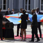 
              Protocol members prepare to cover the casket with the mortal remains of Patrice Lumumba with a Congolese flag during a ceremony at the Egmont Palace in Brussels, Monday, June 20, 2022. On Monday, more than sixty one years after his death, the mortal remains of Congo's first democratically elected prime minister Patrice Lumumba were handed over to his children during an official ceremony in Belgium. (AP Photo/Olivier Matthys)
            